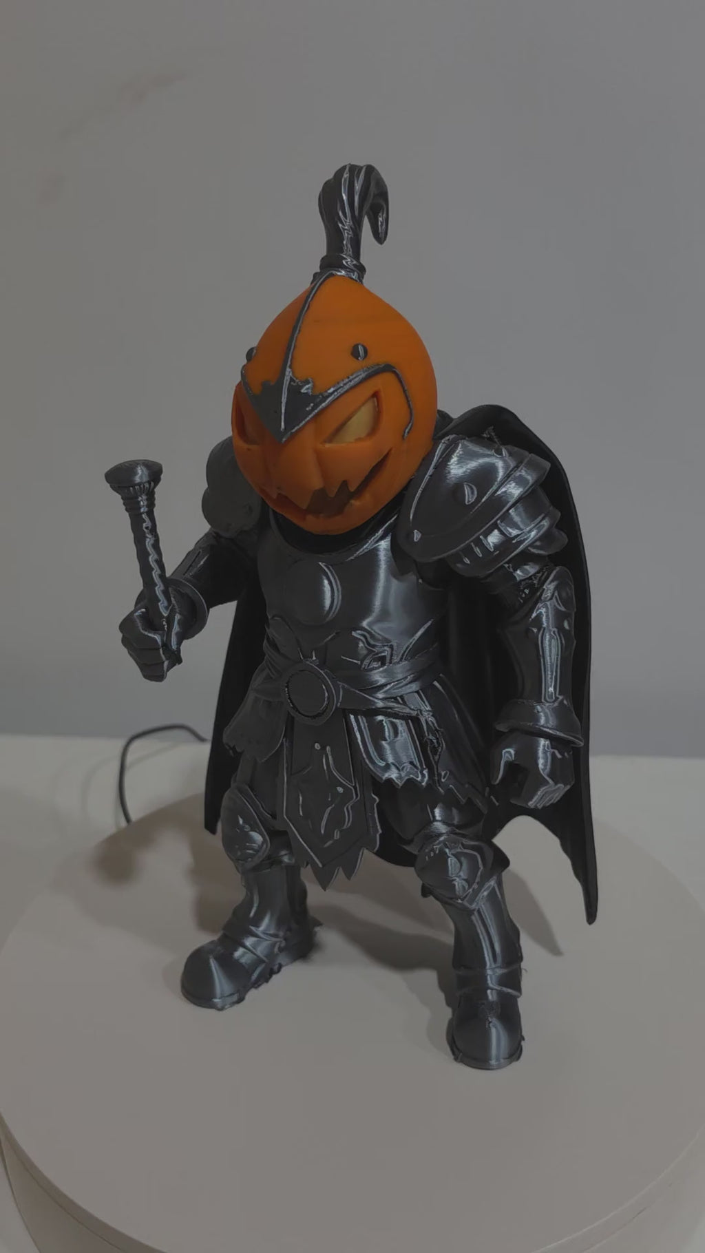 Actual Pumpkin Knight 3D print rotating to show silver-toned armor, orange pumpkin head and black cape.