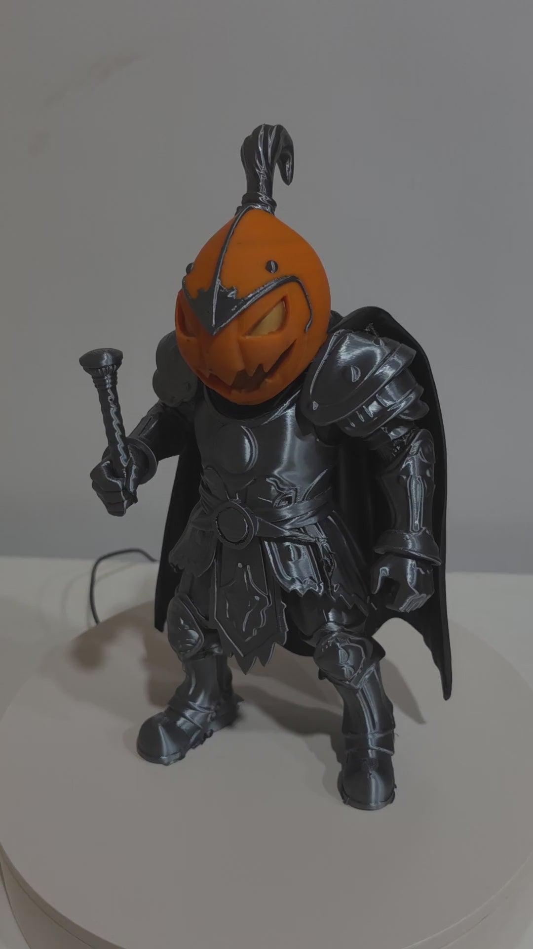 Actual Pumpkin Knight 3D print rotating to show silver-toned armor, orange pumpkin head and black cape.